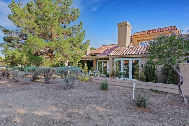 5008 Shoal Creek Cir, Las Vegas, NV 89113 - rear view of house featuring a chimney, a tiled roof, stucco siding, french doors, and a garage