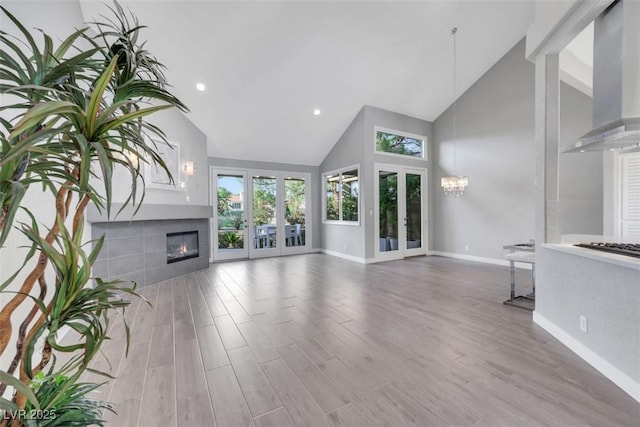 5008 Shoal Creek Cir, Las Vegas, NV 89113 - unfurnished living room with baseboards, high vaulted ceiling, plenty of natural light, a fireplace, and wood finished floors