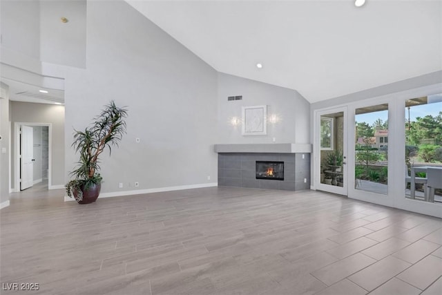 5008 Shoal Creek Cir, Las Vegas, NV 89113 - unfurnished living room featuring high vaulted ceiling, baseboards, a tile fireplace, recessed lighting, and light wood-style flooring