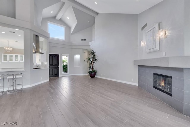 5008 Shoal Creek Cir, Las Vegas, NV 89113 - unfurnished living room featuring a sink, a chandelier, high vaulted ceiling, a tile fireplace, and wood finished floors