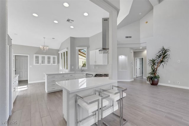 5008 Shoal Creek Cir, Las Vegas, NV 89113 - kitchen with light countertops, baseboards, wall chimney exhaust hood, a sink, and a chandelier