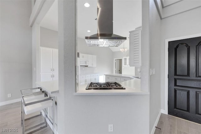 5008 Shoal Creek Cir, Las Vegas, NV 89113 - kitchen featuring island range hood, baseboards, wood finished floors, and stainless steel gas cooktop