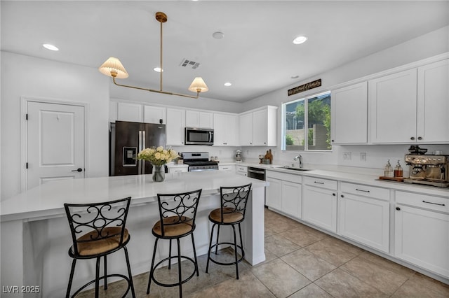 8055 Tank Loop St, Las Vegas, NV 89166 - kitchen with appliances with stainless steel finishes, white cabinetry, a sink, a center island, and pendant lighting