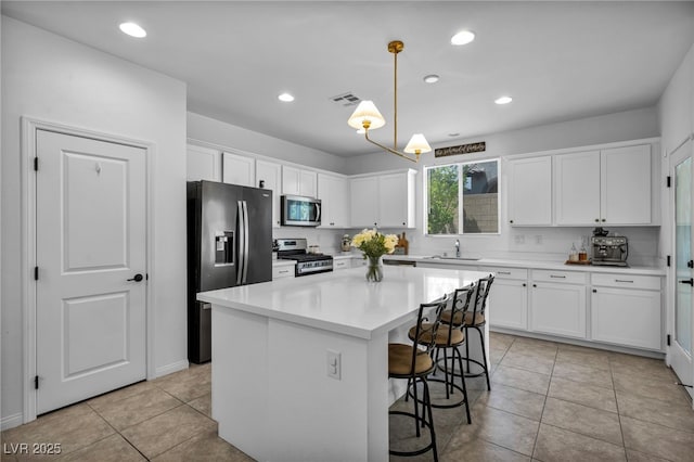 8055 Tank Loop St, Las Vegas, NV 89166 - kitchen featuring stainless steel appliances, white cabinetry, a sink, light tile patterned floors, and a breakfast bar