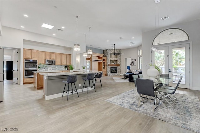 2168 Big Bar Dr, Henderson, NV 89052 - dining area with light wood-style floors, recessed lighting, a stone fireplace, and french doors