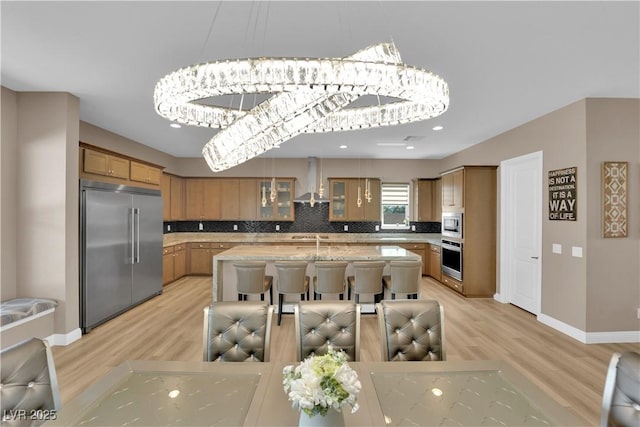 7258 W Le Baron Ave, Las Vegas, NV 89178 - kitchen with built in appliances, wall chimney exhaust hood, light wood-style flooring, decorative backsplash, and recessed lighting