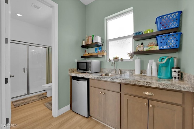 7258 W Le Baron Ave, Las Vegas, NV 89178 - kitchen with open shelves, stainless steel microwave, light wood finished floors, dishwasher, and light stone counters