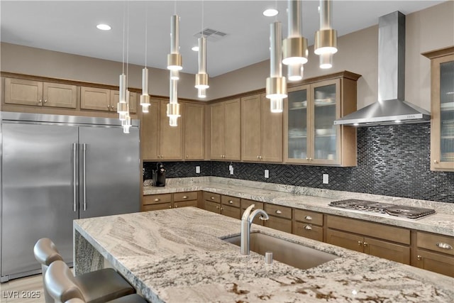 7258 W Le Baron Ave, Las Vegas, NV 89178 - kitchen featuring appliances with stainless steel finishes, wall chimney exhaust hood, a sink, a breakfast bar, and light stone counters