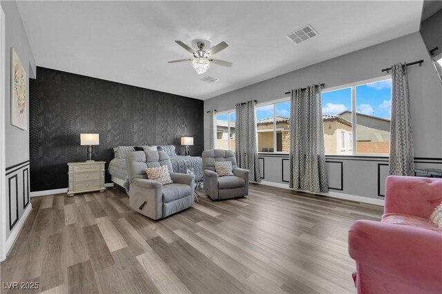 7258 W Le Baron Ave, Las Vegas, NV 89178 - bedroom featuring an accent wall, wallpapered walls, wood finished floors, a ceiling fan, and baseboards