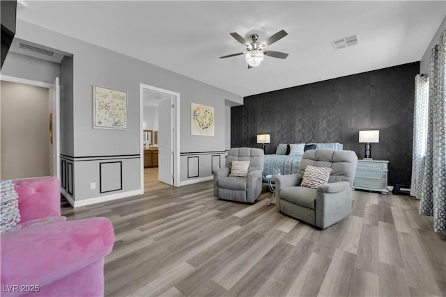 7258 W Le Baron Ave, Las Vegas, NV 89178 - living room with an accent wall, wallpapered walls, a ceiling fan, light wood-style floors, and a wainscoted wall