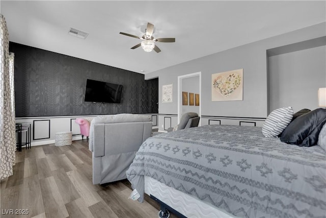 7258 W Le Baron Ave, Las Vegas, NV 89178 - bedroom featuring an accent wall, wallpapered walls, wood finished floors, and ceiling fan