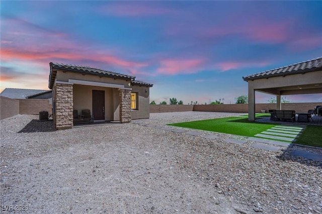 7258 W Le Baron Ave, Las Vegas, NV 89178 - back of property at dusk with stucco siding, a patio area, stone siding, a tiled roof, and central AC unit