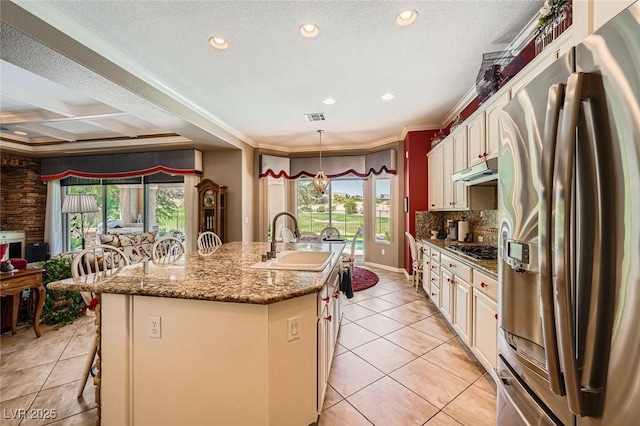 4719 Riva De Romanza St, Las Vegas, NV 89135 - kitchen with stainless steel appliances, light tile patterned floors, an island with sink, a breakfast bar, and tasteful backsplash