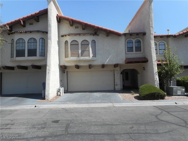5006 Schumann Dr, Las Vegas, NV 89146 - mediterranean / spanish home featuring an attached garage, a tiled roof, driveway, and stucco siding