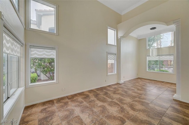 9772 Galahad Point Ct, Las Vegas, NV 89147 - spare room featuring ornate columns, baseboards, arched walkways, crown molding, and stone finish floors