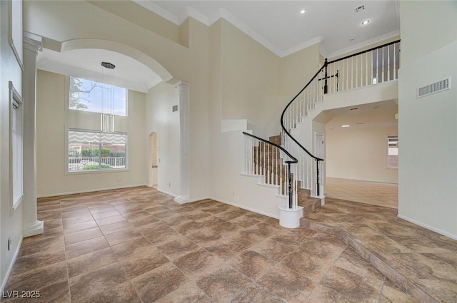 9772 Galahad Point Ct, Las Vegas, NV 89147 - foyer entrance featuring arched walkways, a high ceiling, crown molding, ornate columns, and baseboards
