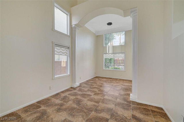 9772 Galahad Point Ct, Las Vegas, NV 89147 - spare room featuring ornate columns, stone finish flooring, baseboards, arched walkways, and a high ceiling