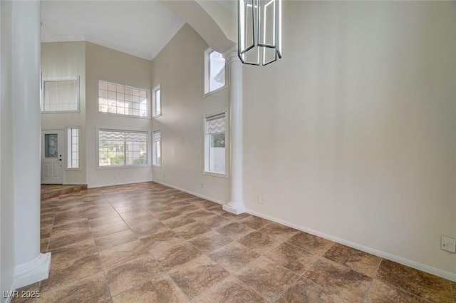 9772 Galahad Point Ct, Las Vegas, NV 89147 - unfurnished dining area with arched walkways, a towering ceiling, baseboards, ornate columns, and stone finish flooring