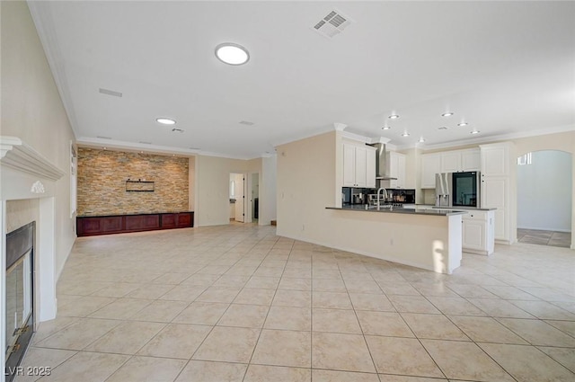 9772 Galahad Point Ct, Las Vegas, NV 89147 - unfurnished living room featuring crown molding, light tile patterned floors, recessed lighting, a glass covered fireplace, and a sink