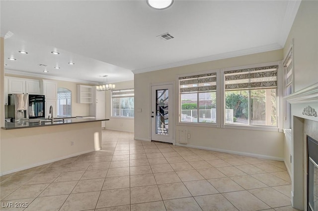 9772 Galahad Point Ct, Las Vegas, NV 89147 - unfurnished living room featuring ornamental molding, a chandelier, light tile patterned floors, a glass covered fireplace, and baseboards