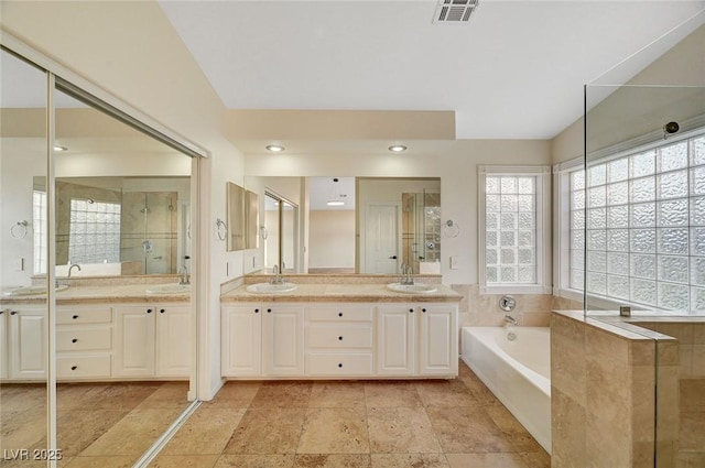 9772 Galahad Point Ct, Las Vegas, NV 89147 - full bath featuring plenty of natural light, double vanity, a bath, and stone tile flooring