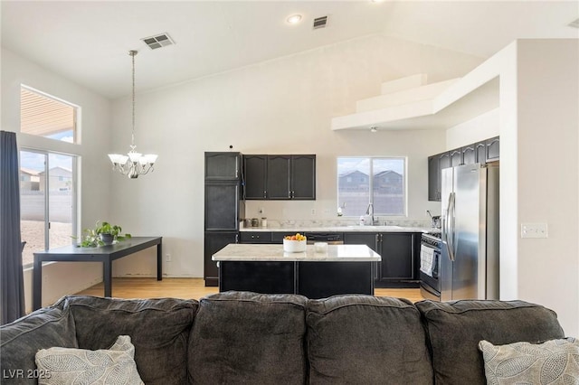 4878 Califa Dr, Las Vegas, NV 89122 - kitchen with open floor plan, appliances with stainless steel finishes, a sink, light countertops, and high vaulted ceiling