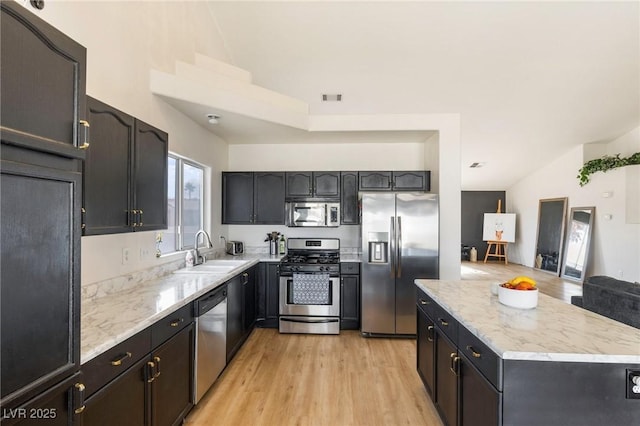 4878 Califa Dr, Las Vegas, NV 89122 - kitchen with stainless steel appliances, a sink, light wood-style flooring, a center island, and lofted ceiling