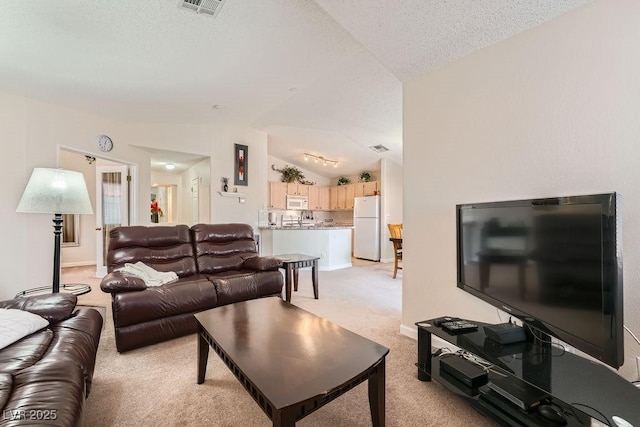 605 Devonhall St Unit 201, Las Vegas, NV 89145 - living area featuring vaulted ceiling, light colored carpet, baseboards, and a textured ceiling