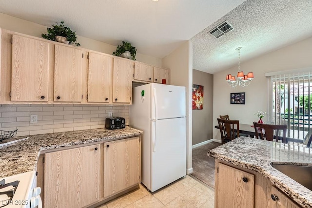 605 Devonhall St Unit 201, Las Vegas, NV 89145 - kitchen featuring freestanding refrigerator, vaulted ceiling, backsplash, light stone counters, and a chandelier