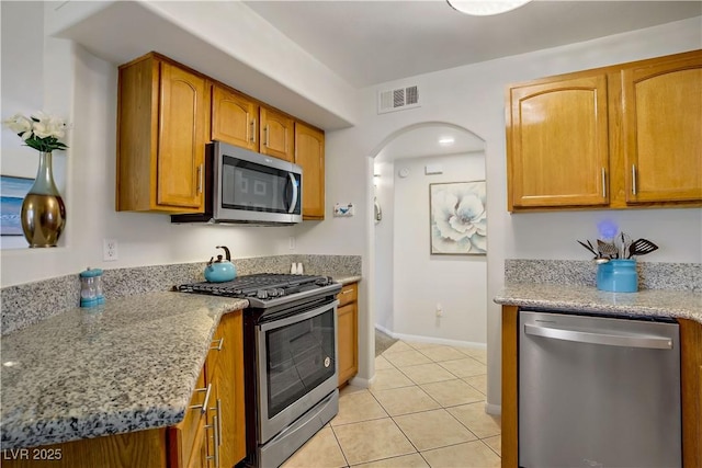 698 S Racetrack Rd Unit 1714, Henderson, NV 89015 - kitchen featuring stainless steel appliances, light tile patterned floors, light stone counters, baseboards, and arched walkways