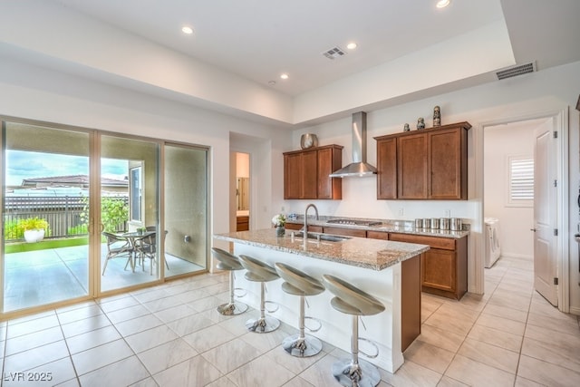 6728 Regency Ridge Ct, Las Vegas, NV 89148 - kitchen featuring wall chimney range hood, washing machine and dryer, plenty of natural light, stainless steel gas cooktop, and recessed lighting