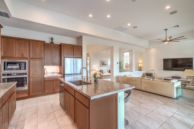 6728 Regency Ridge Ct, Las Vegas, NV 89148 - kitchen featuring stainless steel appliances, a sink, open floor plan, brown cabinets, and recessed lighting
