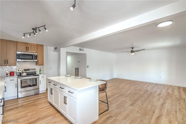 1600 E Mcdonald Ave, North Las Vegas, NV 89030 - kitchen with stainless steel appliances, a kitchen breakfast bar, ceiling fan, light wood-style floors, and light countertops