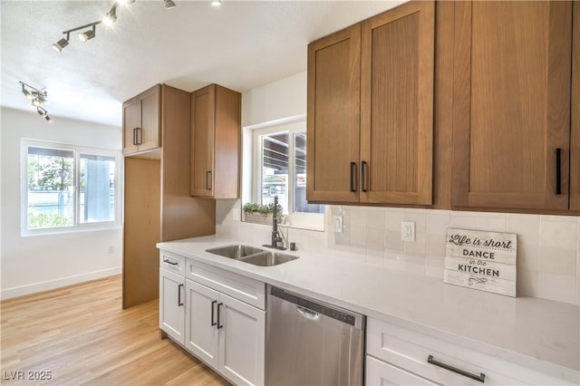 1600 E Mcdonald Ave, North Las Vegas, NV 89030 - kitchen featuring dishwasher, a sink, light countertops, tasteful backsplash, and light wood-style floors
