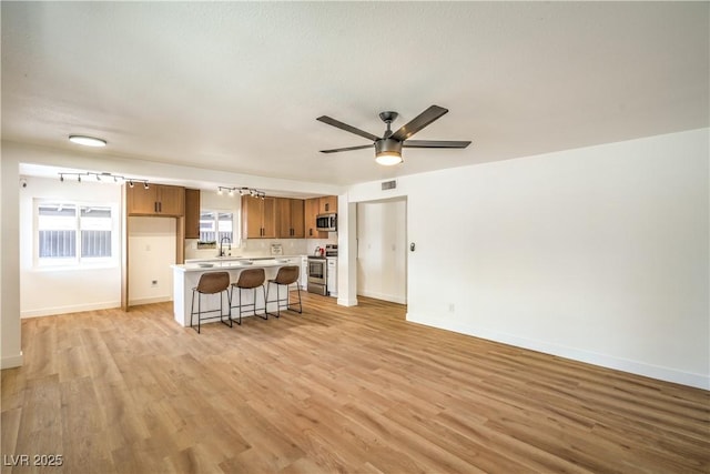 1600 E Mcdonald Ave, North Las Vegas, NV 89030 - kitchen with stainless steel appliances, light countertops, a kitchen breakfast bar, brown cabinetry, and a ceiling fan