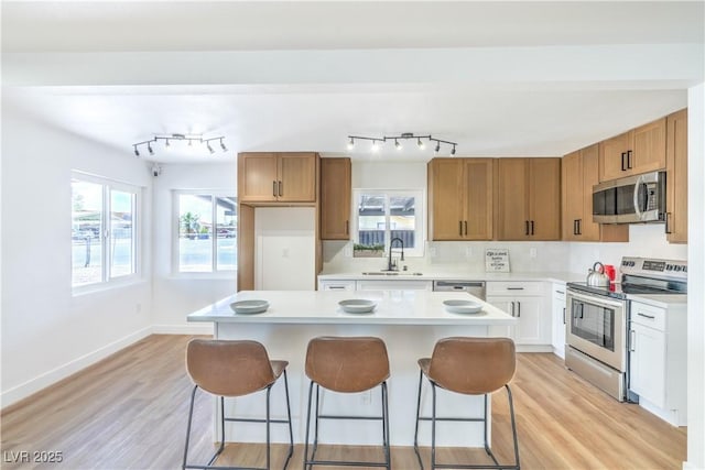 1600 E Mcdonald Ave, North Las Vegas, NV 89030 - kitchen with stainless steel appliances, a sink, a breakfast bar, light countertops, and light wood-style flooring