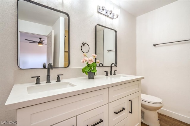 1600 E Mcdonald Ave, North Las Vegas, NV 89030 - bathroom with toilet, double vanity, wood finished floors, baseboards, and a ceiling fan