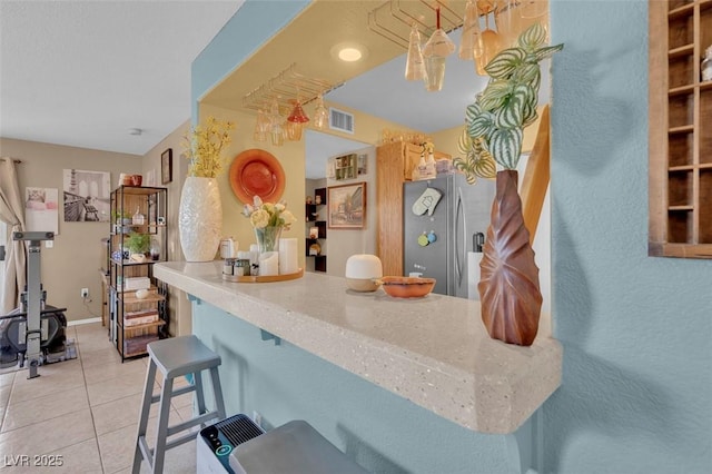 7950 W Flamingo Rd Unit 1003, Las Vegas, NV 89147 - kitchen with stainless steel fridge, light tile patterned floors, a breakfast bar area, and a chandelier