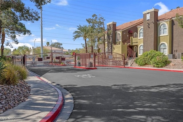 7950 W Flamingo Rd Unit 1003, Las Vegas, NV 89147 - view of asphalt road with a gate, curbs, street lighting, sidewalks, and a gated entry