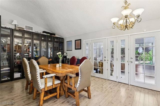 3201 Beacon Shores Cir, Las Vegas, NV 89117 - dining area with a chandelier, a textured ceiling, vaulted ceiling, wood finished floors, and french doors