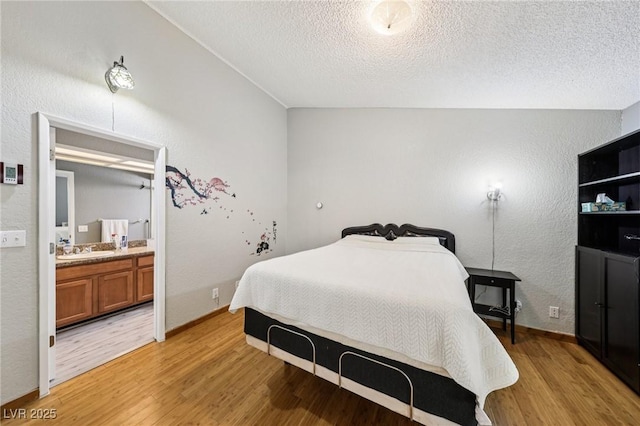 3201 Beacon Shores Cir, Las Vegas, NV 89117 - bedroom featuring light wood-type flooring, a textured ceiling, a sink, ensuite bathroom, and a textured wall