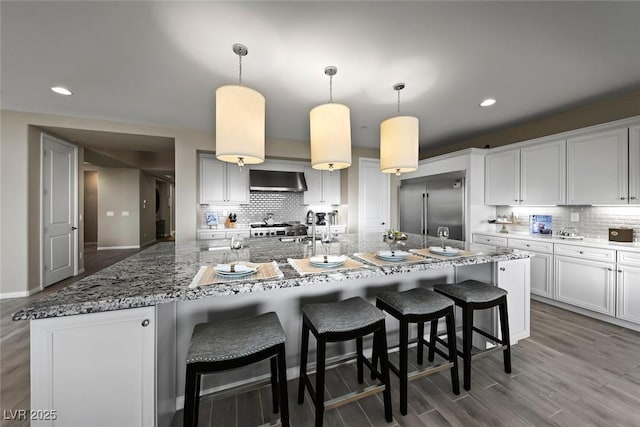 4702 Amazing View St, Las Vegas, NV 89129 - kitchen featuring stainless steel built in refrigerator, wall chimney range hood, tasteful backsplash, a large island, and wood finished floors