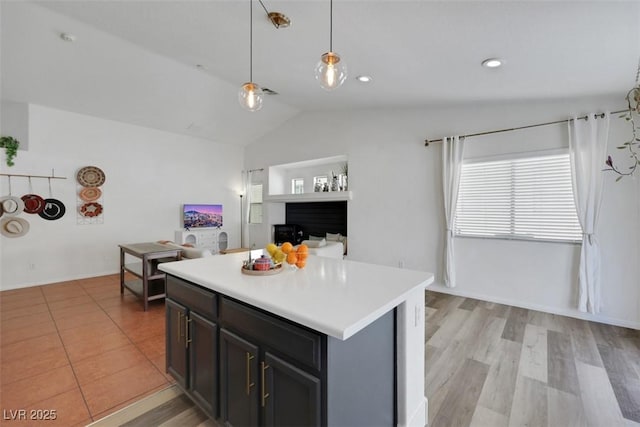 520 Blackbird Knoll Ct, North Las Vegas, NV 89084 - kitchen with vaulted ceiling, light countertops, hanging light fixtures, a kitchen island, and light wood-style floors