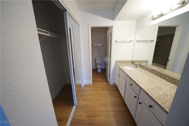 2606 S Durango Dr Unit 165, Las Vegas, NV 89117 - bathroom featuring vanity, wood finished floors, toilet, a textured wall, and baseboards