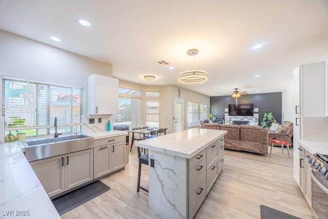 747 Canyon Crest Dr, Las Vegas, NV 89123 - kitchen with a sink, light wood finished floors, a ceiling fan, light stone counters, and stainless steel gas stove