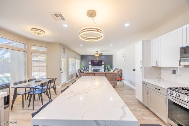 747 Canyon Crest Dr, Las Vegas, NV 89123 - kitchen with light wood-style flooring, baseboards, gas stove, recessed lighting, and a kitchen island