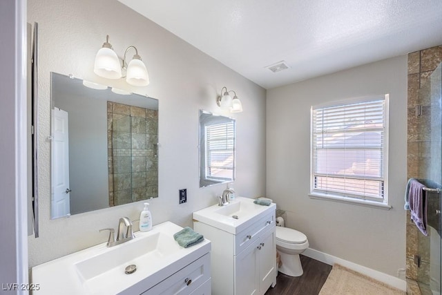 747 Canyon Crest Dr, Las Vegas, NV 89123 - bathroom with two vanities, toilet, wood finished floors, baseboards, and a tile shower