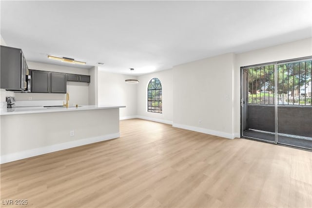 2964 Juniper Hills Blvd Unit 104, Las Vegas, NV 89142 - unfurnished living room featuring healthy amount of natural light, light wood-style floors, baseboards, and a sink