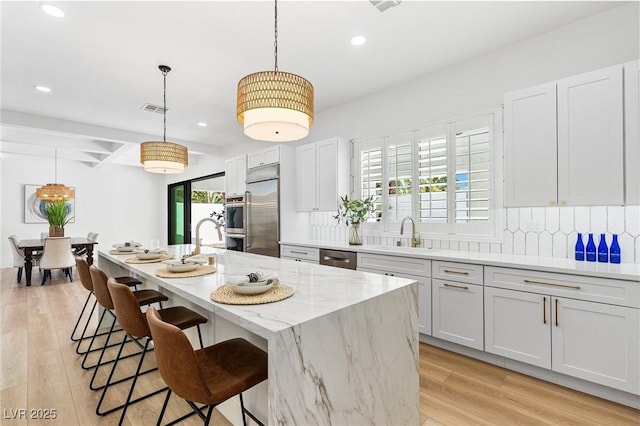 5225 Villa Dante Ave, Las Vegas, NV 89141 - kitchen with recessed lighting, tasteful backsplash, appliances with stainless steel finishes, a breakfast bar area, and light stone countertops