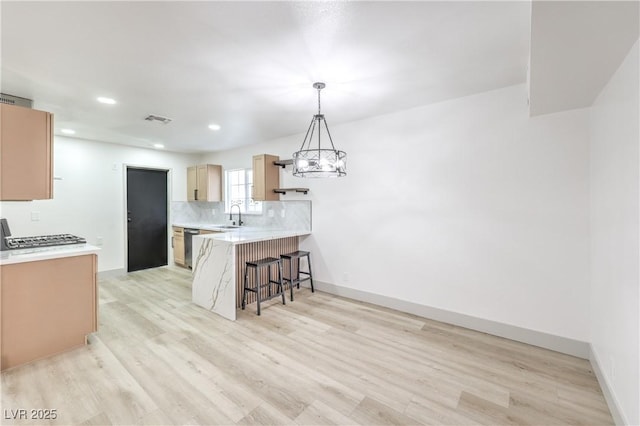 1805 Amboy Dr, Las Vegas, NV 89108 - kitchen with a peninsula, a breakfast bar area, light wood-style flooring, tasteful backsplash, and recessed lighting